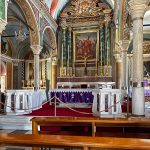 The dramatic interior is a richly decorated Baroque-style with marble details, gilded altars, painted ceilings, and religious iconography that contrasts sharply with the stark island landscape outside. (3877)