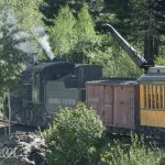 The steam locomotive pauses beside a trackside water tank to replenish its tender, as it consumes thousands of gallons of water on the climb to Silverton. This stop an essential part of the trip just as it was more than a century ago.